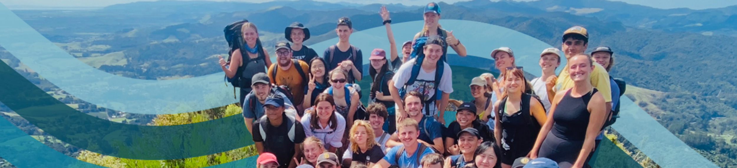 Group of students with hiking gear on top of a scenic overlook of trees